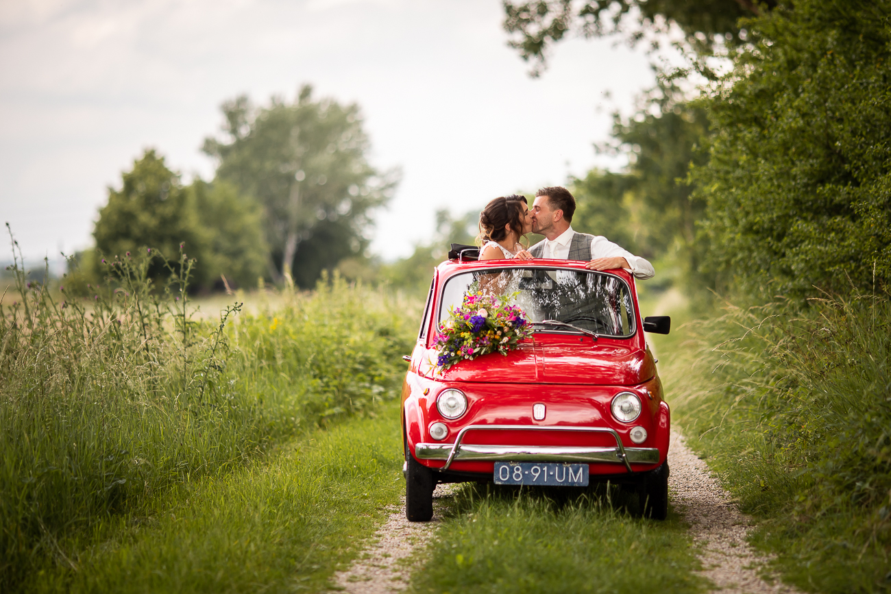 Bruidspaar in een rode Fiat 500