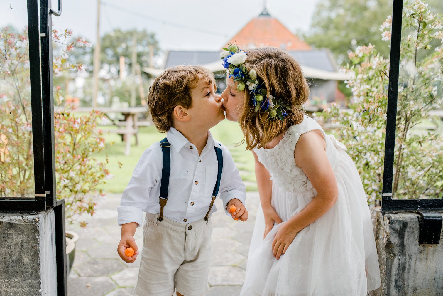 Bruidskinderen geven elkaar een kus op de bruiloft