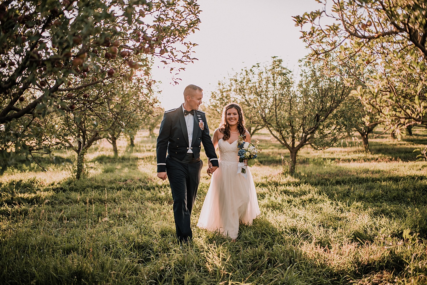 Bruidspaar loopt door een appel boomgaard